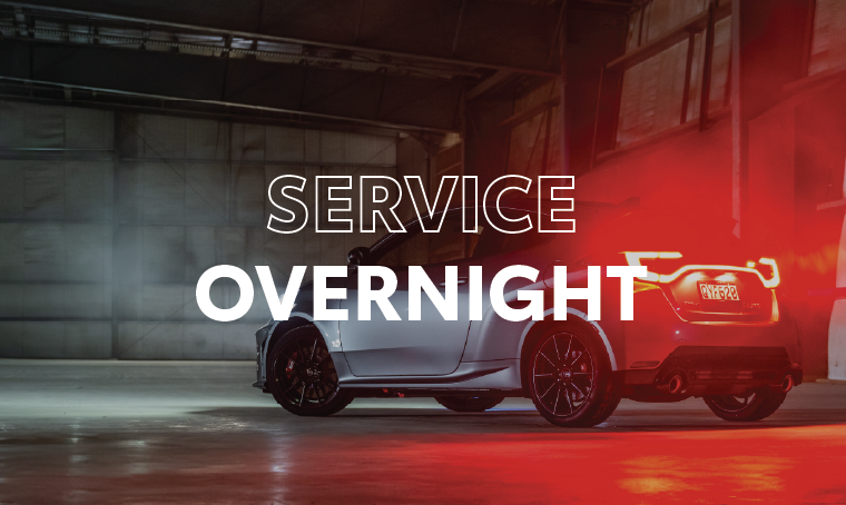 Rear three quarter view of a Toyota Yaris with the break lights illuminated and overlay text that reads, "service overnight"