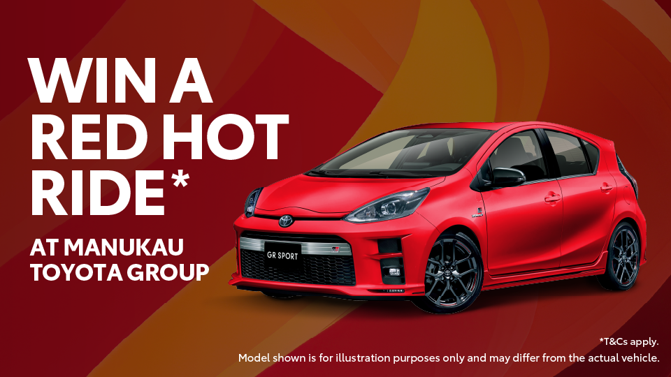 Promotional banner showing a bright red Toyota Aqua GR Sport car on a red and orange gradient background. Large white text on the left reads ‘WIN A RED HOT RIDE AT MANUKAU TOYOTA GROUP.’ Smaller text at the bottom says ‘Model shown is for illustration purposes only and may differ from the actual vehicle.’ A note in the bottom right corner states ‘T&Cs apply.’